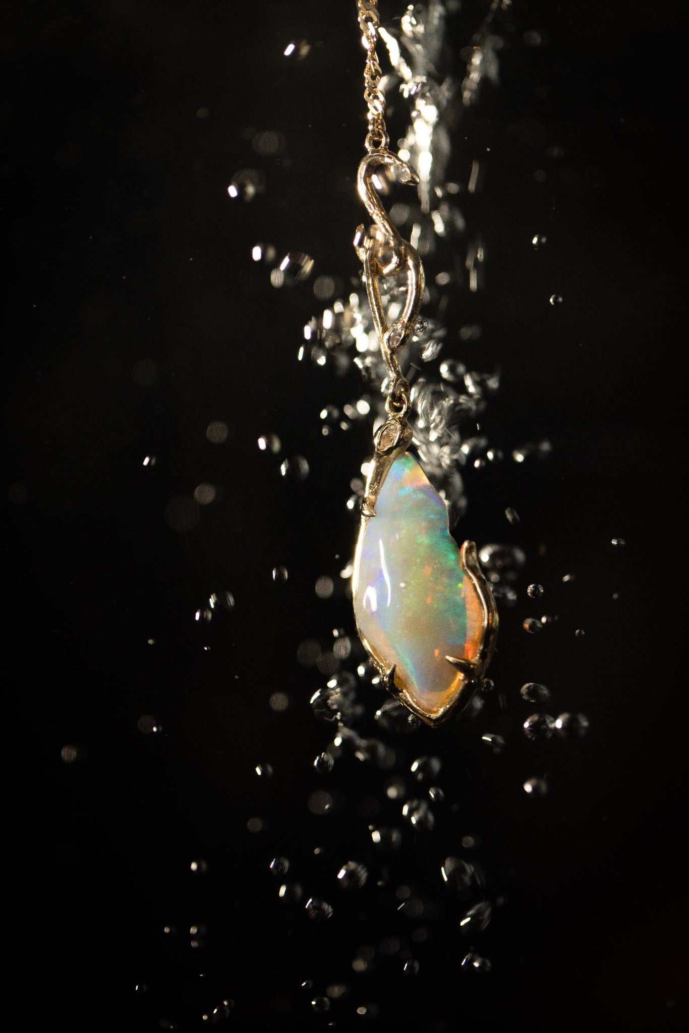One-of-one opal and gold serpent pendant surrounded by bubbles against black